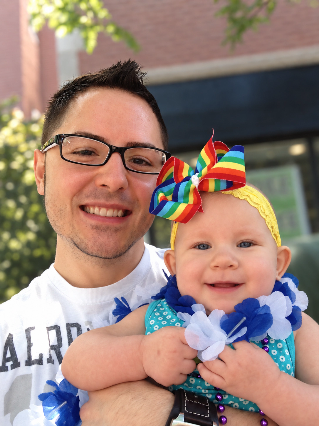 Frank Golden and Sophia smiling together outdoors, with Sophia wearing a rainbow bow.