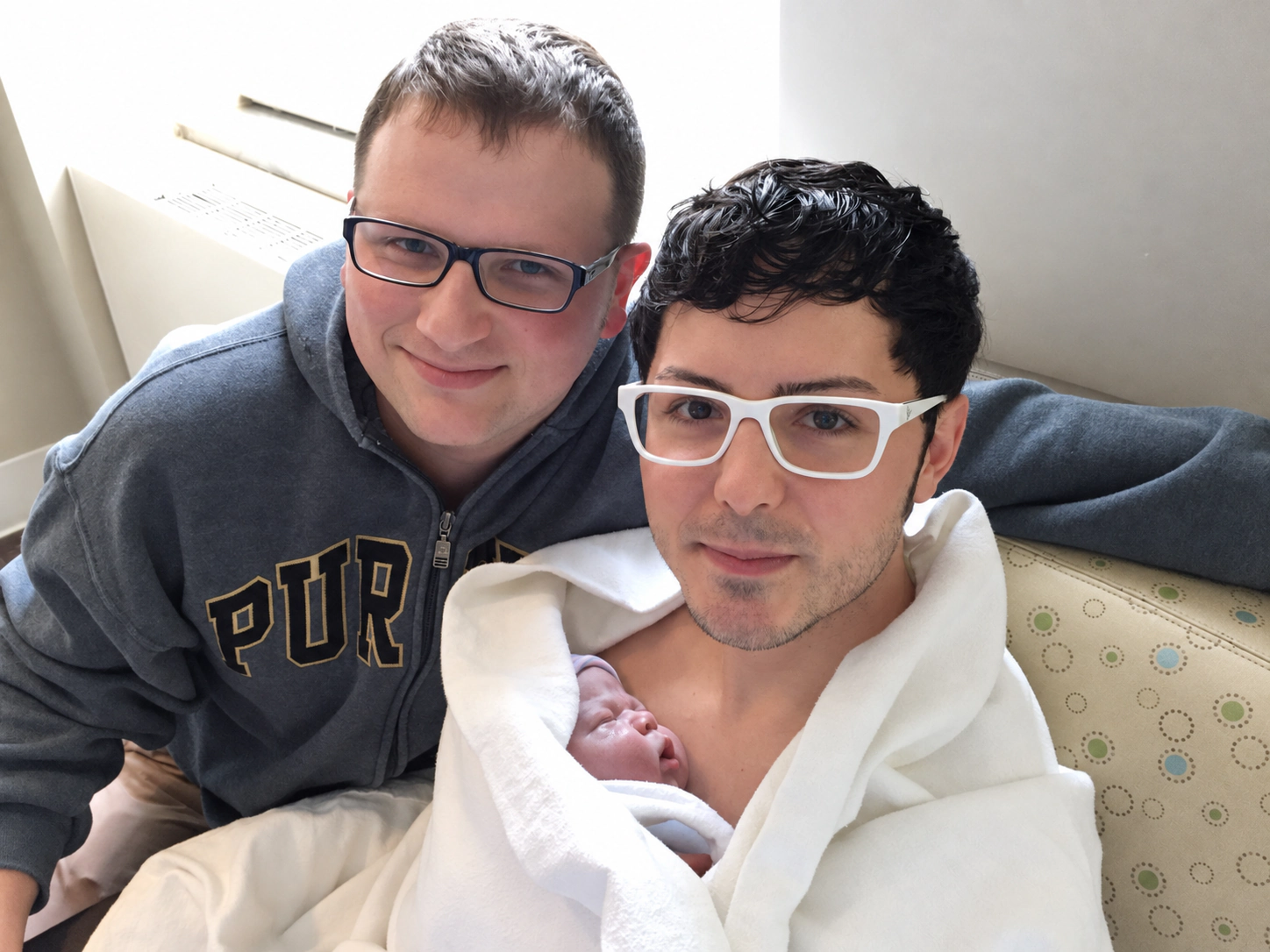 Frank and Adam Golden together with their newborn resting on Frank’s chest.