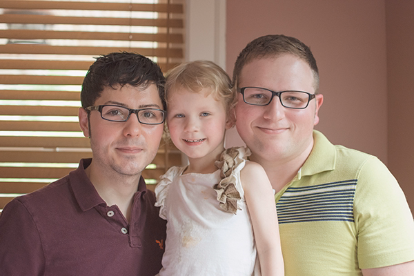 Frank-Adam-Sophia-resized two dads smile with their daughter between them.