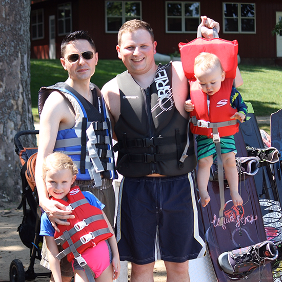 Golden-family-Lake-Life-Jackets two dads hold their daughter and son in life jackets.