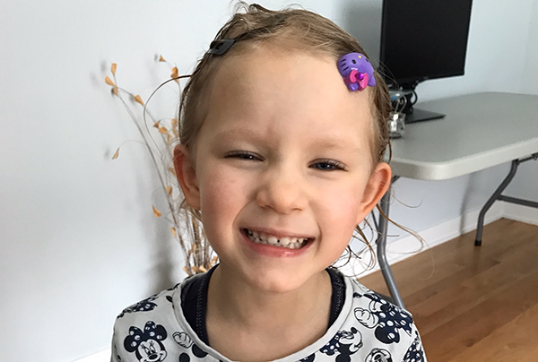 little girl with a purple clip in her hair smiles big.
