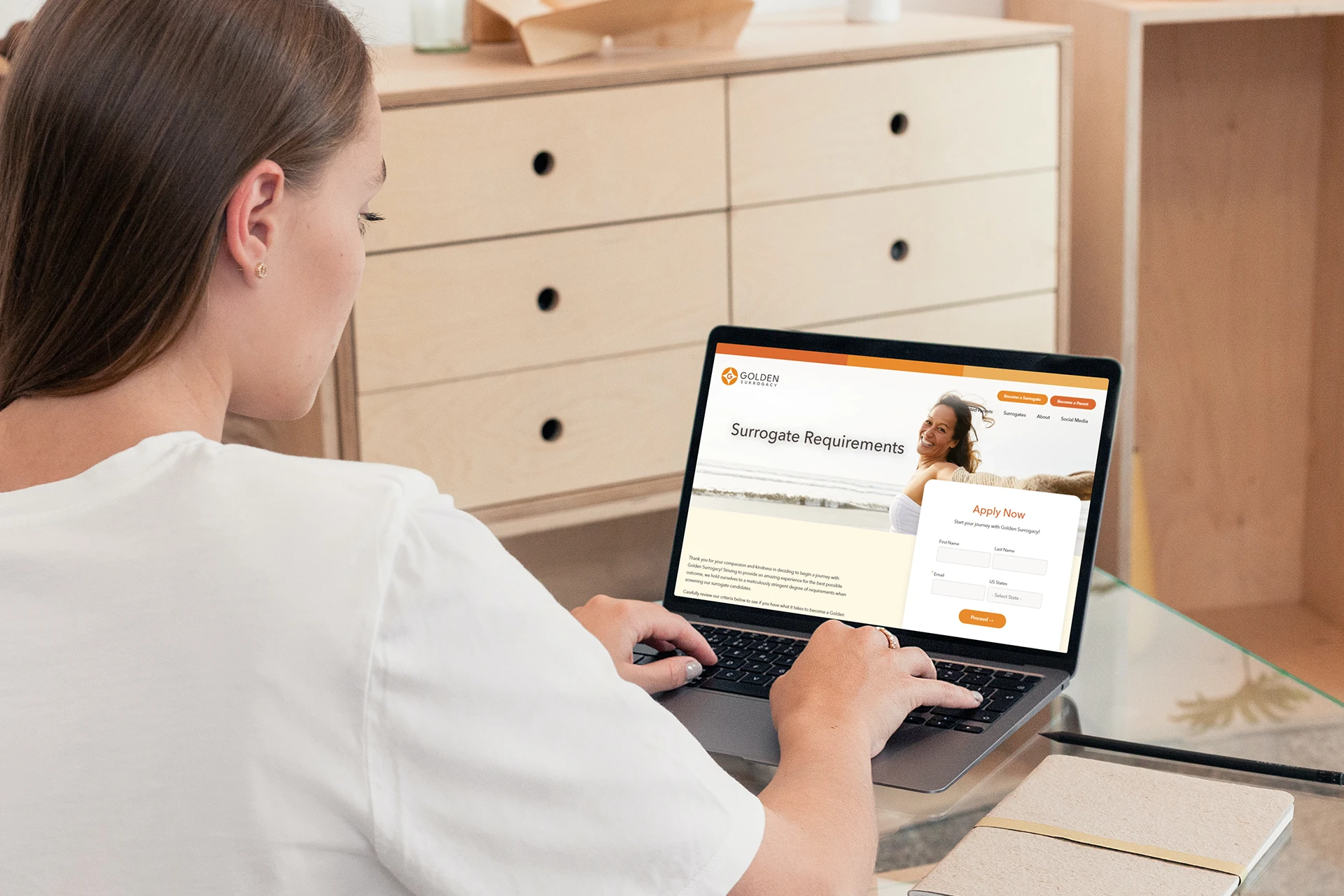 Woman in white shirt looking at Surrogate requirements on her laptop.