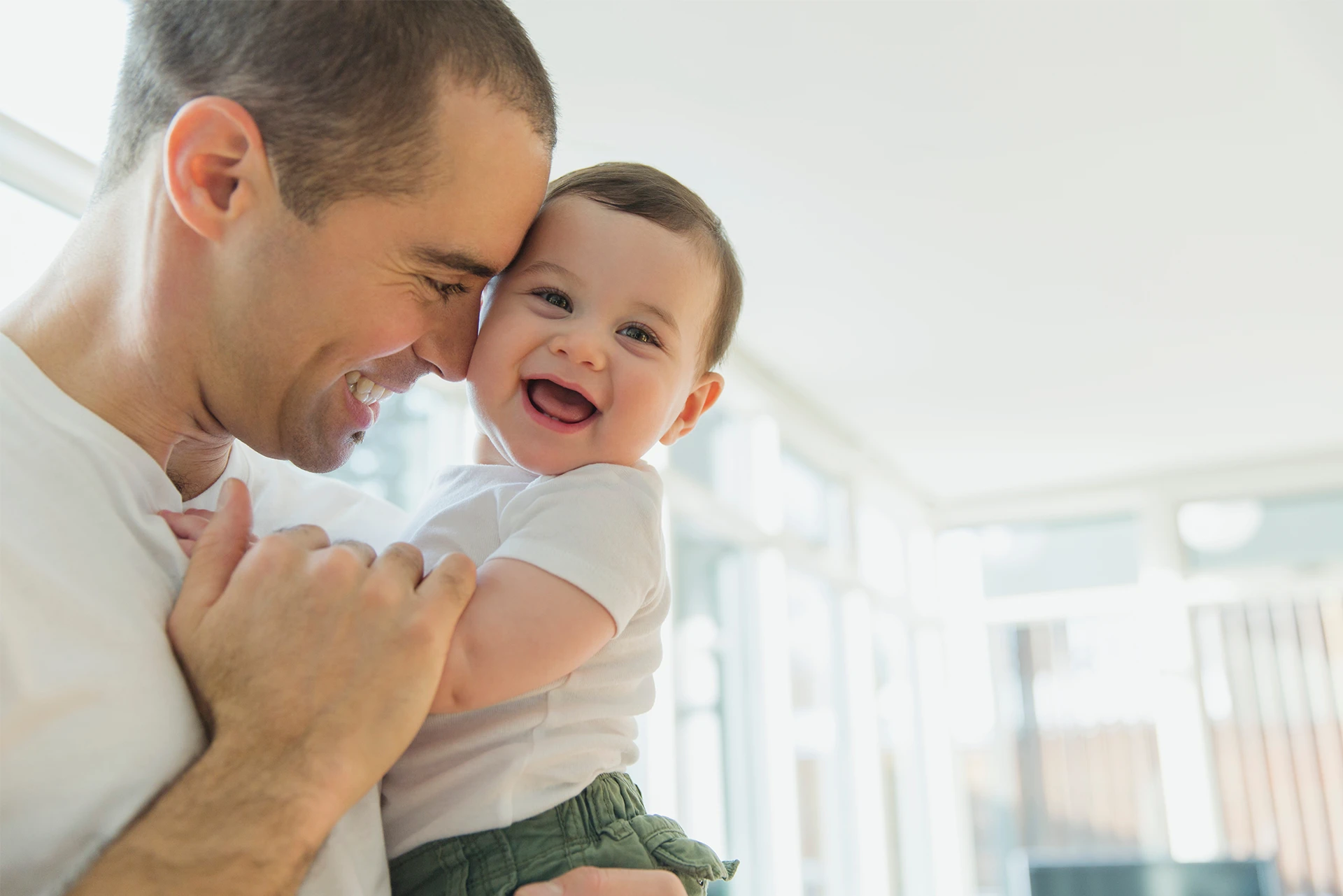 Intended father holding his baby while they both smile.